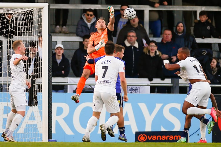 Woking's Craig Ross punches clear.