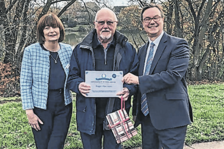 Jonathan Lord MP and Lorraine Buchanan, chief officer of Citizens Advice Woking, present Roger Harrison with a certificate for 25 years of volunteering for CAW
