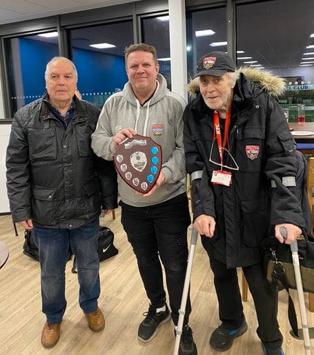 Knaphill chairman Chris Drane, centre, and president Dave Holloway, right, receive the Dave Taylor Memorial Shield from its sponsor Mick Elliott after the Knappers’ 6-1 victory over the Sheers at the Eastwood Centre last Saturday (January 13, 2024) in the Cherry Red Records Combined Counties League