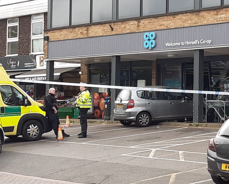 A vehicle straddles the kerb after crashing through the door of the Co-op store in Horsell this morning