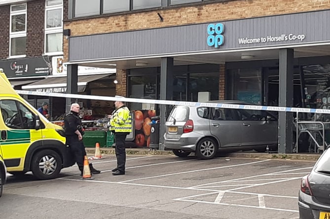 A vehicle straddles the kerb after crashing through the door of the Co-op store in Horsell this morning