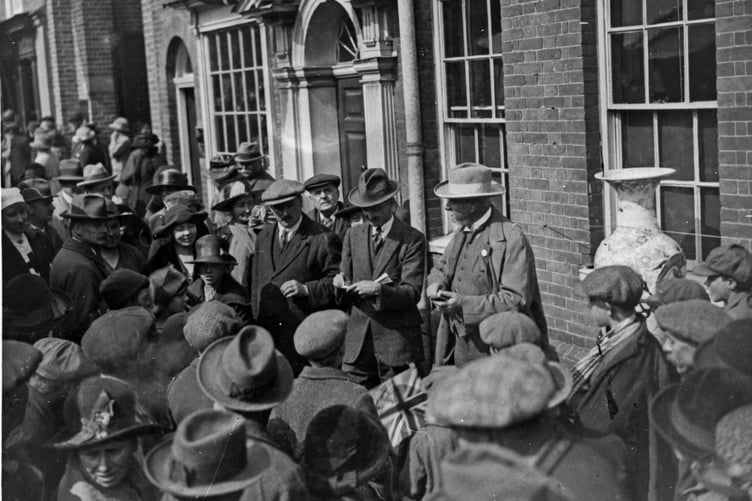 An auction taking place outside J Alfred Eggar's premises. The man with the book could be keeping a tally of the bids perhaps. Was the large vase one of the auction items - perhaps raising funds for the war effort?