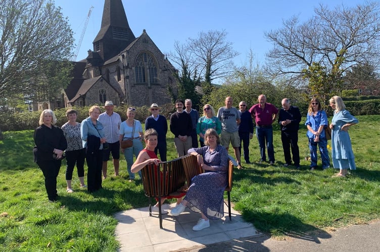 Nicola and Mandy Maguire, pictured on the bench, celebrate the unveiling of their father's bench with the community, Samaritans and Weybridge Men’s Shed