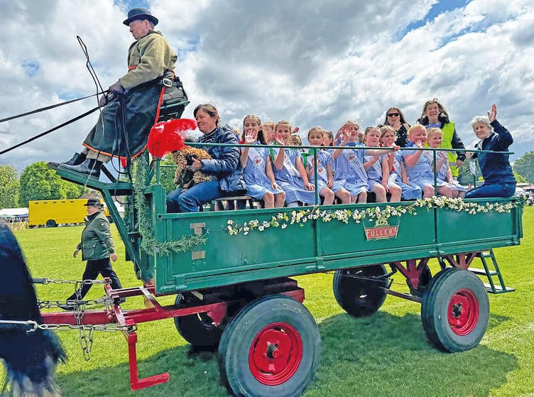 St Lawrence Primary School’s maypole dancers enjoy a ride around the arena in John Medhurst’s brewery dray at this year’s carnival