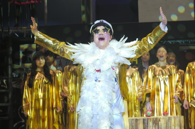 The larger than life Elton John (Junyi Perrett) bursts onto the stage, along with a gospel choir dressed in gold lame.