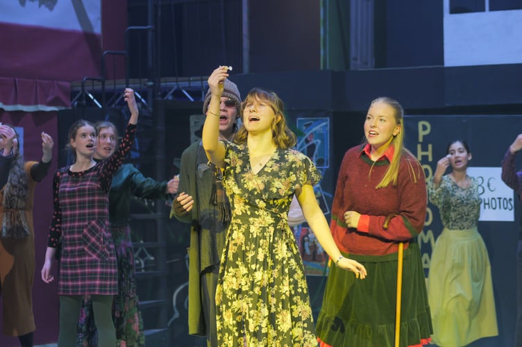 Amelie (Kate Brazendale) takes the blind beggar Adrien (Ben Hallett) on a tour of Paris, describing all the things she is seeing, including the sweet shop. Pictured are (front) Erin Henderson and (back left to right); the young Amelie (Siena Phipps), Millie Kirtley, Ben Hallett, Kate Brazendale and Amber Oshiga.